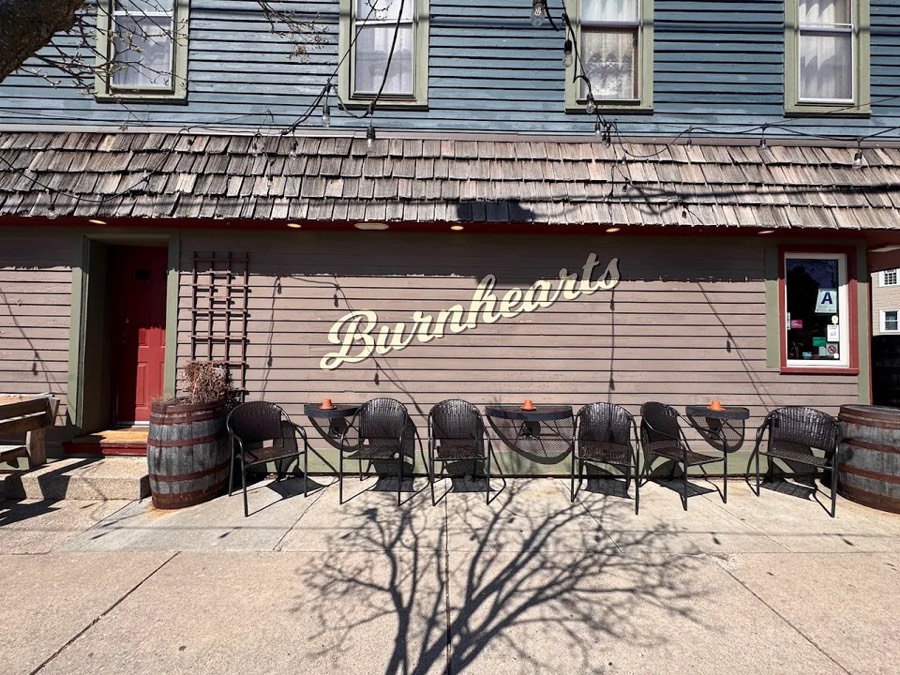 Burnhearts from the pavement, the script sign across the front and wicker chairs lined up under it