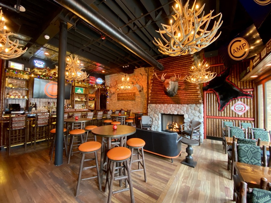Deer Camp — antler chandeliers, a stone fireplace and orange-topped stools