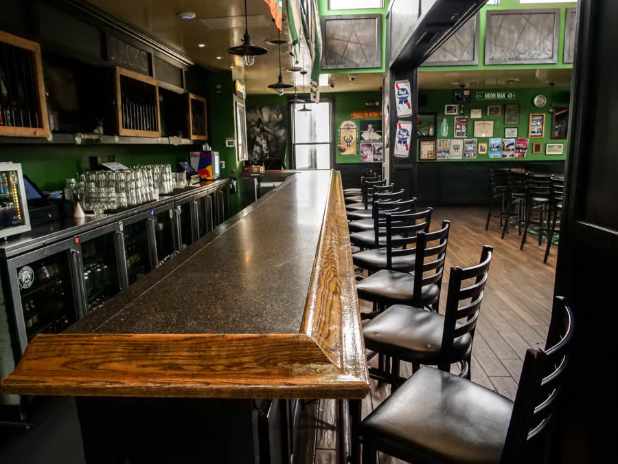 The long dark bar at Jacks American Pub, green walls covered in framed photos