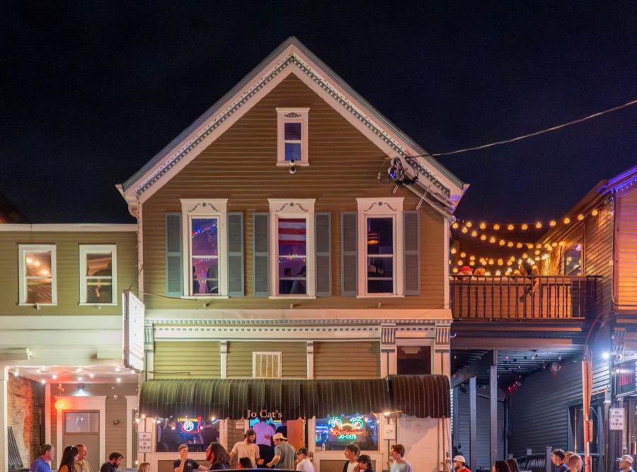 Jo-Cats at night from across the street, neon in the windows and string lights over the patio
