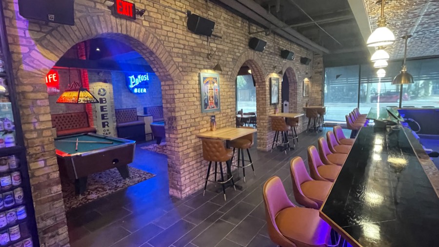 Inside Water Street Brewery — brick arches, neon beer signs, a pool table and a long bar of pink stools
